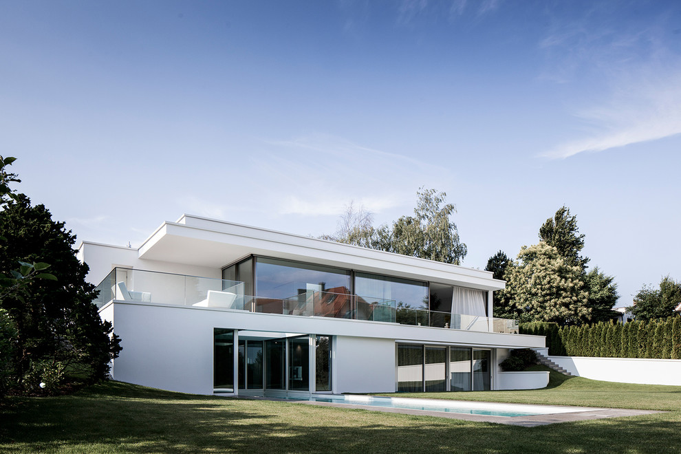Design ideas for an expansive modern two-storey stucco white house exterior in Frankfurt with a flat roof.