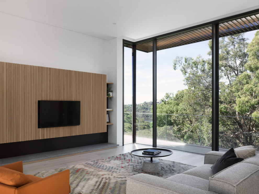 Inspiration for an expansive modern open concept living room in Sydney with white walls, light hardwood floors, a wall-mounted tv and beige floor.