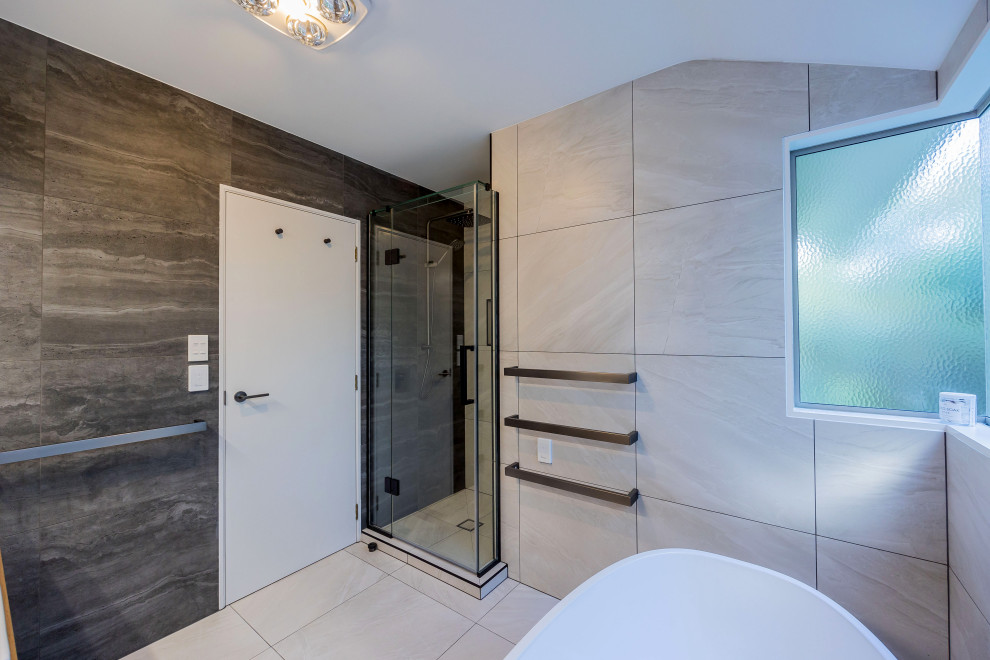 Свежая идея для дизайна: маленькая главная ванная комната в стиле модернизм с светлыми деревянными фасадами, отдельно стоящей ванной, душем в нише, серой плиткой, керамической плиткой, полом из керамогранита, монолитной раковиной, столешницей из искусственного камня, белым полом, душем с распашными дверями, белой столешницей, тумбой под одну раковину и подвесной тумбой для на участке и в саду - отличное фото интерьера