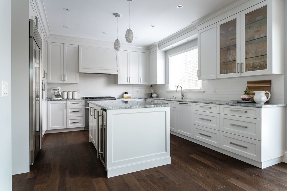 Example of a large transitional u-shaped medium tone wood floor and brown floor eat-in kitchen design in Vancouver with an undermount sink, recessed-panel cabinets, white cabinets, granite countertops, white backsplash, subway tile backsplash, stainless steel appliances, an island and multicolored countertops