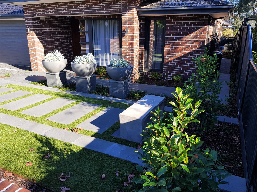 Photo of a mid-sized modern front yard partial sun formal garden for summer in Melbourne with with flowerbed and natural stone pavers.