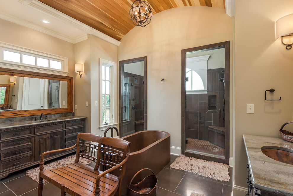 This is an example of a country master bathroom in Other with an undermount sink, dark wood cabinets, a freestanding tub, an alcove shower, gray tile, beige walls, grey benchtops and raised-panel cabinets.