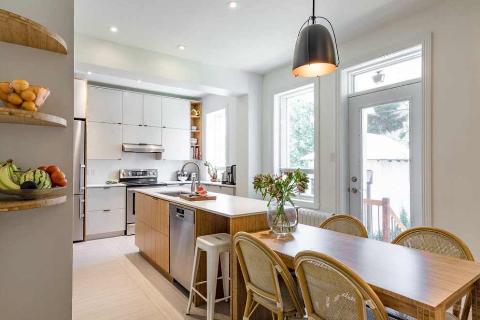Mid-sized transitional separate kitchen in Montreal with an undermount sink, flat-panel cabinets, light wood cabinets, solid surface benchtops, stainless steel appliances, linoleum floors, with island, beige floor and white benchtop.