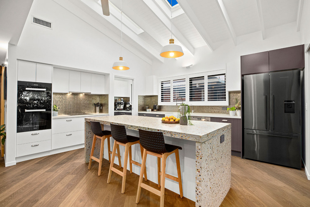 Inspiration for an expansive contemporary l-shaped open plan kitchen in Other with a double-bowl sink, concrete benchtops, metallic splashback, porcelain splashback, stainless steel appliances, medium hardwood floors, with island, brown floor, exposed beam and white cabinets.