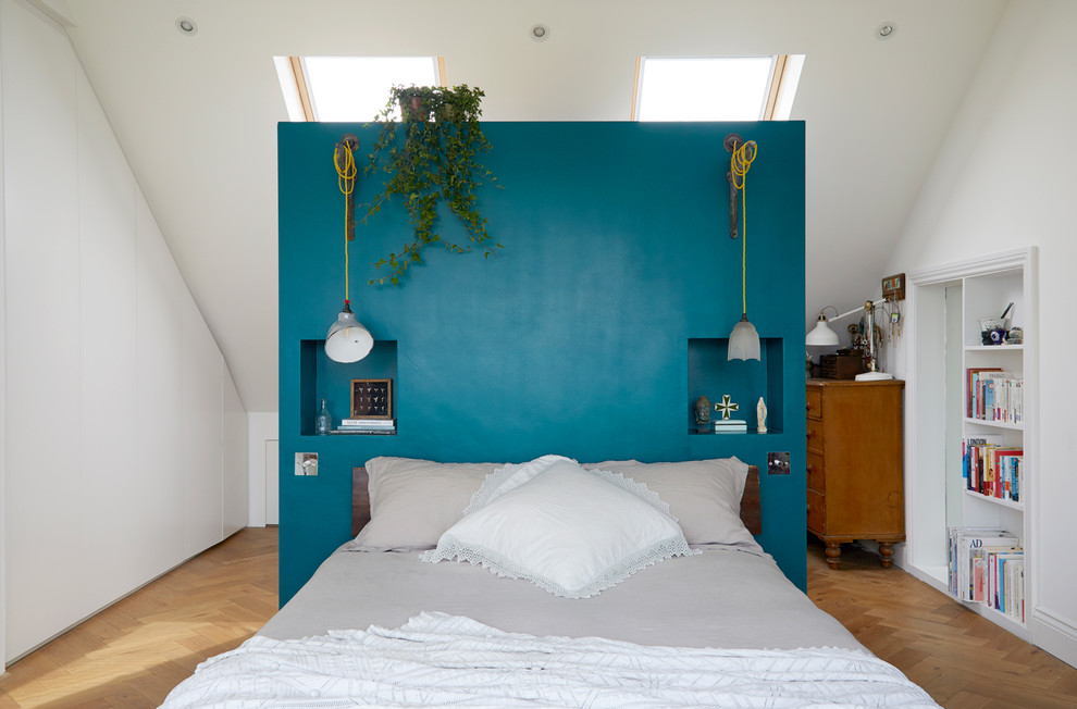This is an example of an eclectic bedroom in London with white walls, medium hardwood floors and brown floor.