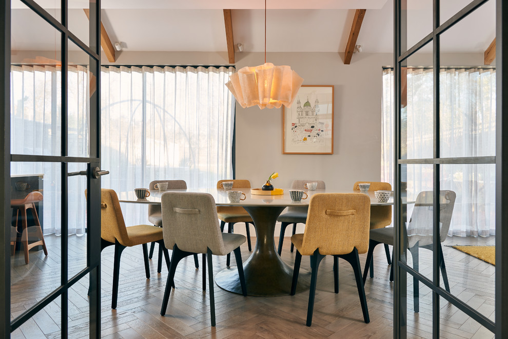 Cette image montre une grande salle à manger ouverte sur le salon design avec un sol en bois brun, un sol marron et un mur blanc.