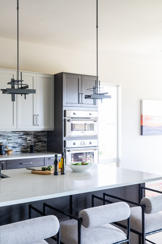 Aménagement d'une cuisine contemporaine fermée et de taille moyenne avec un évier encastré, un placard à porte shaker, des portes de placard blanches, un plan de travail en quartz modifié, une crédence multicolore, une crédence en carrelage métro, un électroménager en acier inoxydable, parquet clair, îlot et un plan de travail blanc.