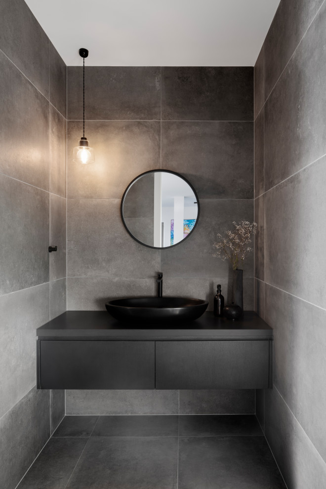 Design ideas for a large contemporary cloakroom in Melbourne with flat-panel cabinets, black cabinets, a two-piece toilet, grey tiles, porcelain tiles, grey walls, ceramic flooring, a pedestal sink, wooden worktops, grey floors, black worktops and a floating vanity unit.