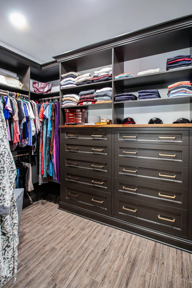 This is an example of a mid-sized transitional gender-neutral walk-in wardrobe in Cleveland with recessed-panel cabinets, brown cabinets, ceramic floors and brown floor.