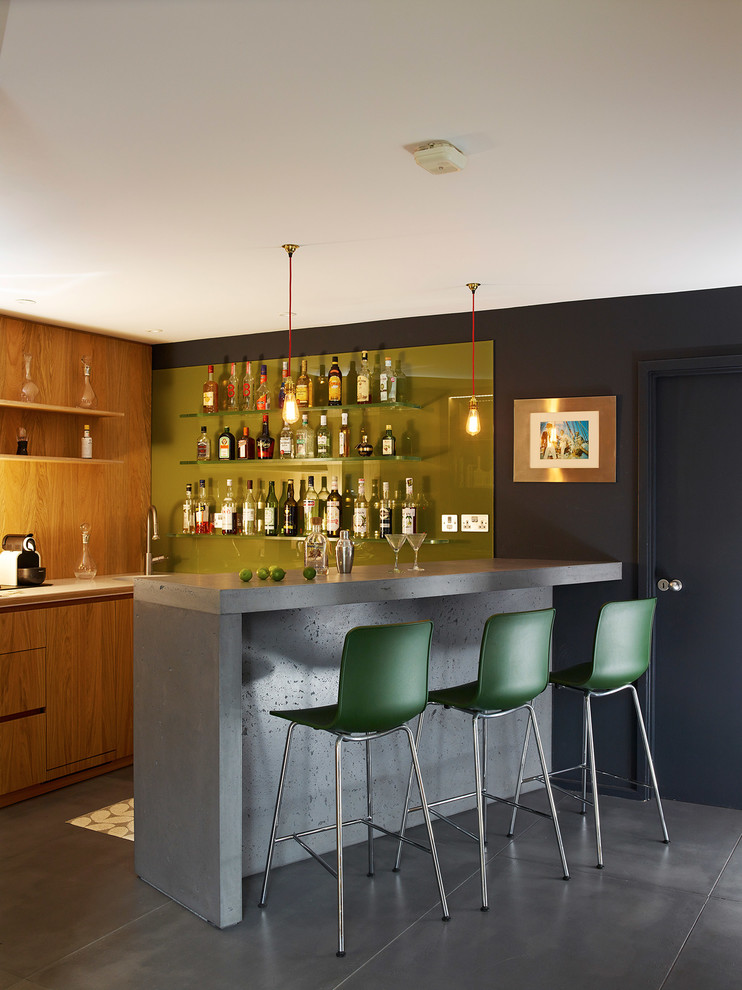 Photo of a contemporary home bar in London with concrete benchtops and concrete floors.