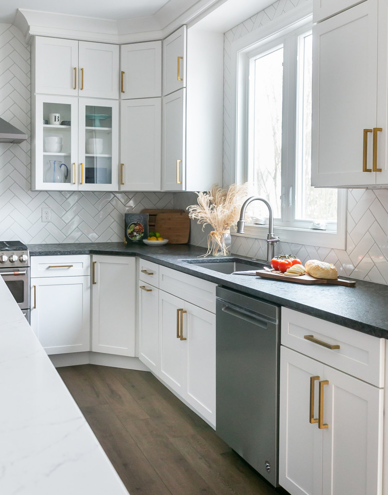 Example of a large transitional l-shaped brown floor kitchen pantry design in Baltimore with a drop-in sink, shaker cabinets, white cabinets, quartz countertops, white backsplash, ceramic backsplash, stainless steel appliances, an island and white countertops