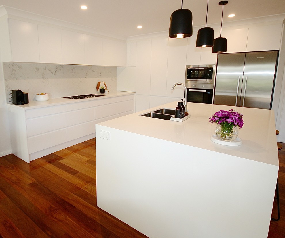 Inspiration for a mid-sized modern l-shaped eat-in kitchen in Sydney with an undermount sink, flat-panel cabinets, white cabinets, quartz benchtops, grey splashback, stone slab splashback, stainless steel appliances, medium hardwood floors and with island.