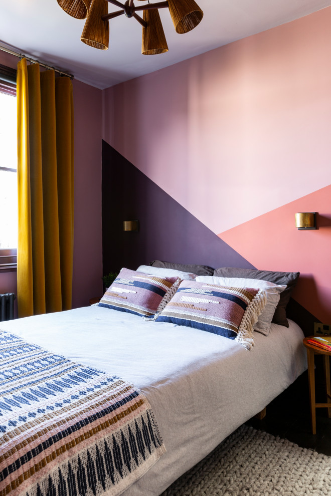 Photo of a mid-sized eclectic guest bedroom in London with pink walls, dark hardwood floors, no fireplace and brown floor.