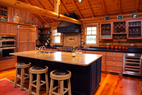 Example of a mid-sized mountain style galley light wood floor and beige floor enclosed kitchen design with a double-bowl sink, raised-panel cabinets, light wood cabinets, granite countertops, beige backsplash, porcelain backsplash, stainless steel appliances and an island