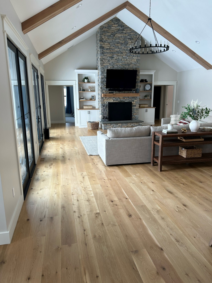 Inspiration for a large contemporary open concept living room in Bridgeport with white walls, medium hardwood floors, a standard fireplace, a stone fireplace surround, brown floor and exposed beam.