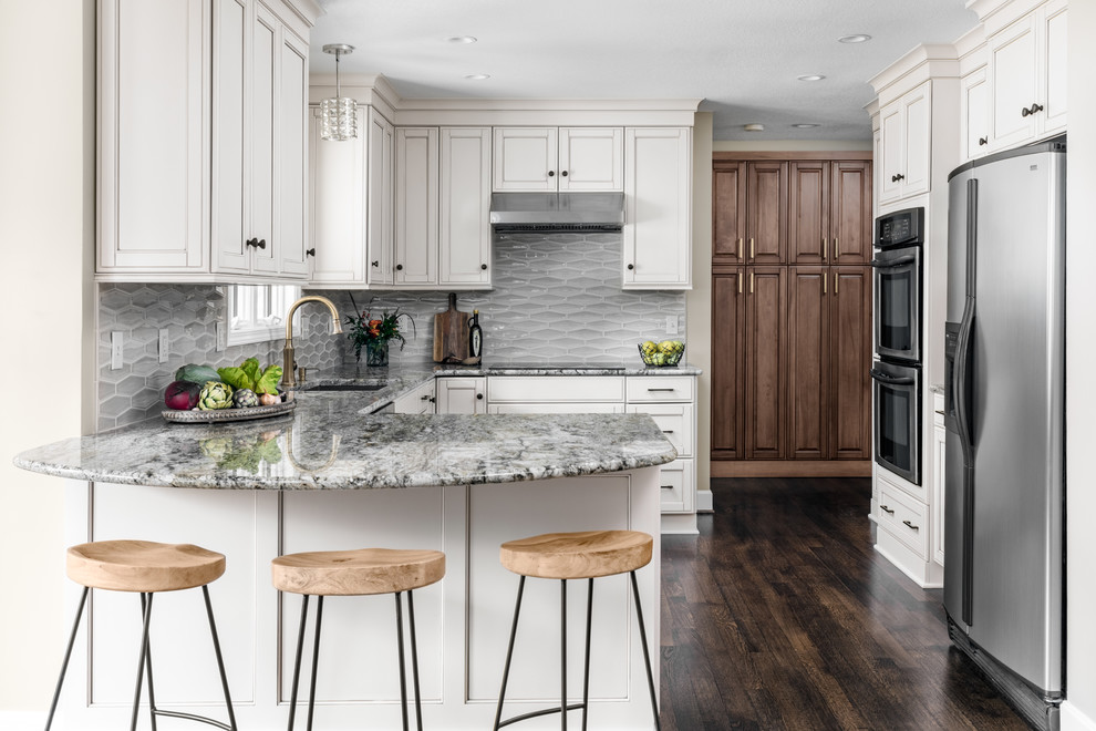 Example of a small country u-shaped dark wood floor eat-in kitchen design in Kansas City with an undermount sink, shaker cabinets, white cabinets, granite countertops, gray backsplash, ceramic backsplash, stainless steel appliances, a peninsula and gray countertops