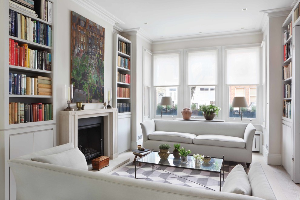 Photo of a mid-sized contemporary enclosed living room in London with a library, white walls, light hardwood floors, a standard fireplace and a concrete fireplace surround.