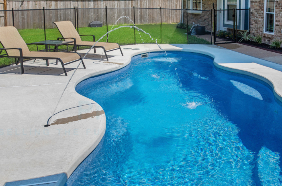 Pool - mid-sized backyard custom-shaped pool idea with decking