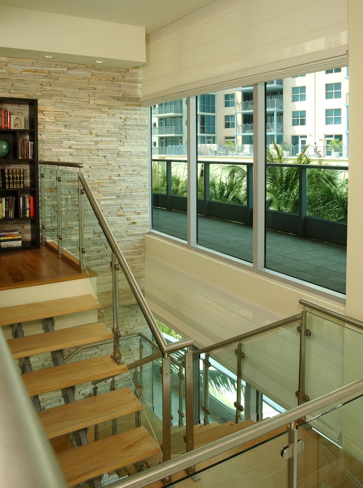 Photo of a mid-sized contemporary wood u-shaped staircase in Miami with open risers and glass railing.