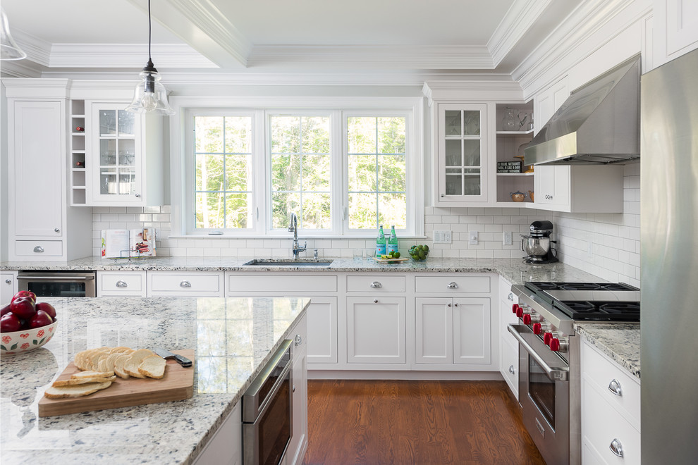 Mid-sized traditional l-shaped eat-in kitchen in Boston with a single-bowl sink, shaker cabinets, white cabinets, granite benchtops, white splashback, subway tile splashback, stainless steel appliances, dark hardwood floors and with island.