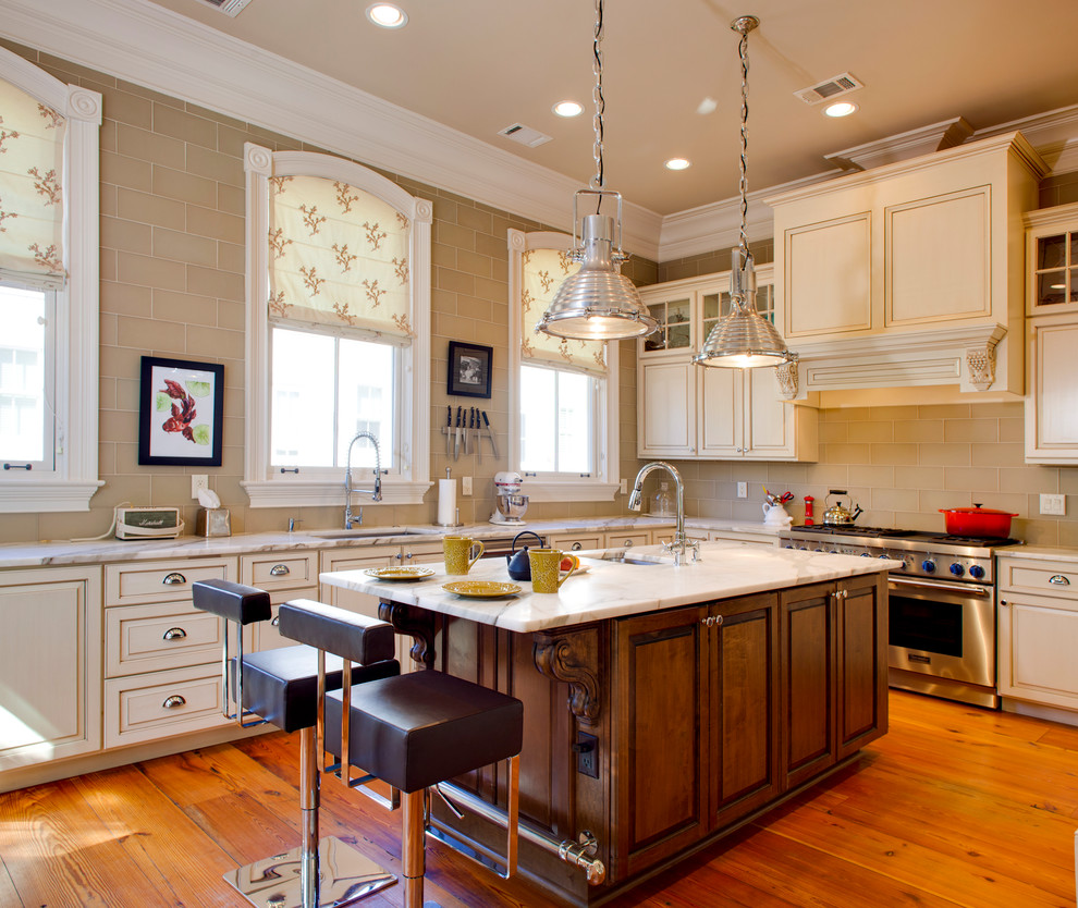 This is an example of a traditional l-shaped kitchen in Atlanta with an undermount sink, raised-panel cabinets, beige cabinets, beige splashback, subway tile splashback, stainless steel appliances, medium hardwood floors and with island.