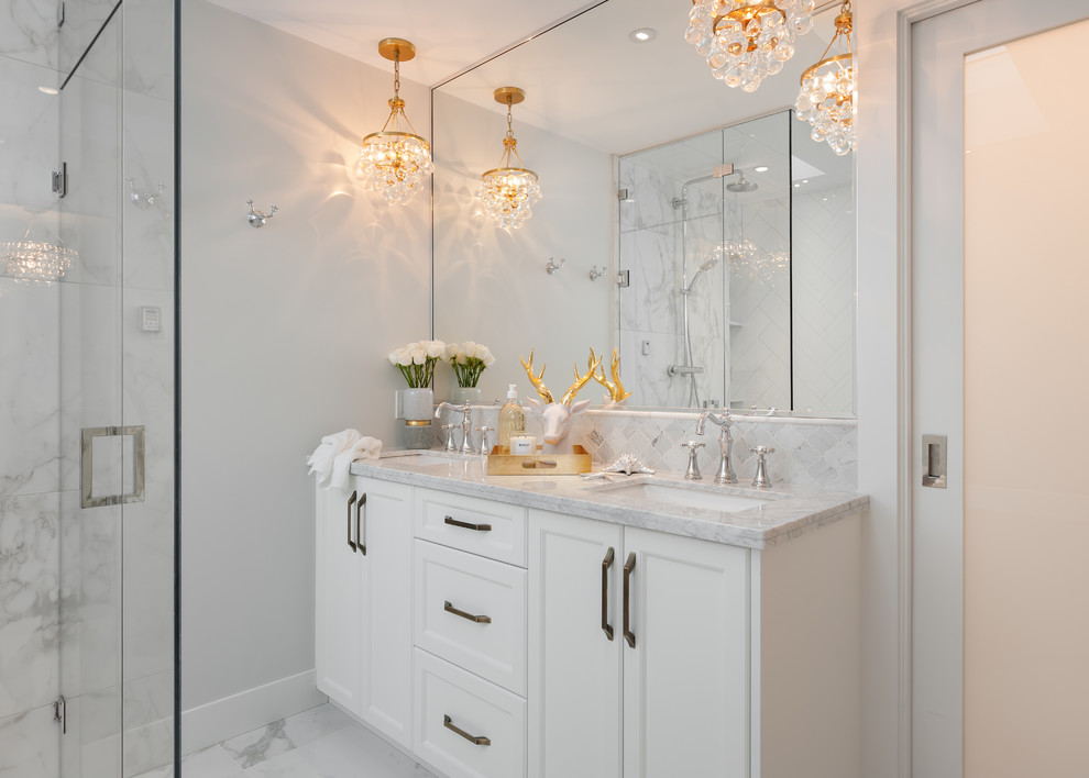 Design ideas for a mid-sized transitional master bathroom in Vancouver with recessed-panel cabinets, white cabinets, a freestanding tub, a corner shower, white tile, porcelain tile, grey walls, porcelain floors, an undermount sink and marble benchtops.