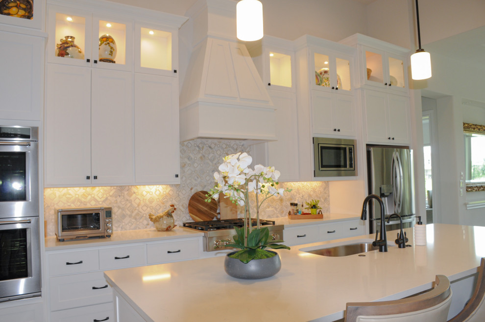 Example of a large transitional single-wall dark wood floor, brown floor and coffered ceiling open concept kitchen design in Austin with a drop-in sink, shaker cabinets, white cabinets, quartzite countertops, multicolored backsplash, stone tile backsplash, stainless steel appliances, an island and white countertops