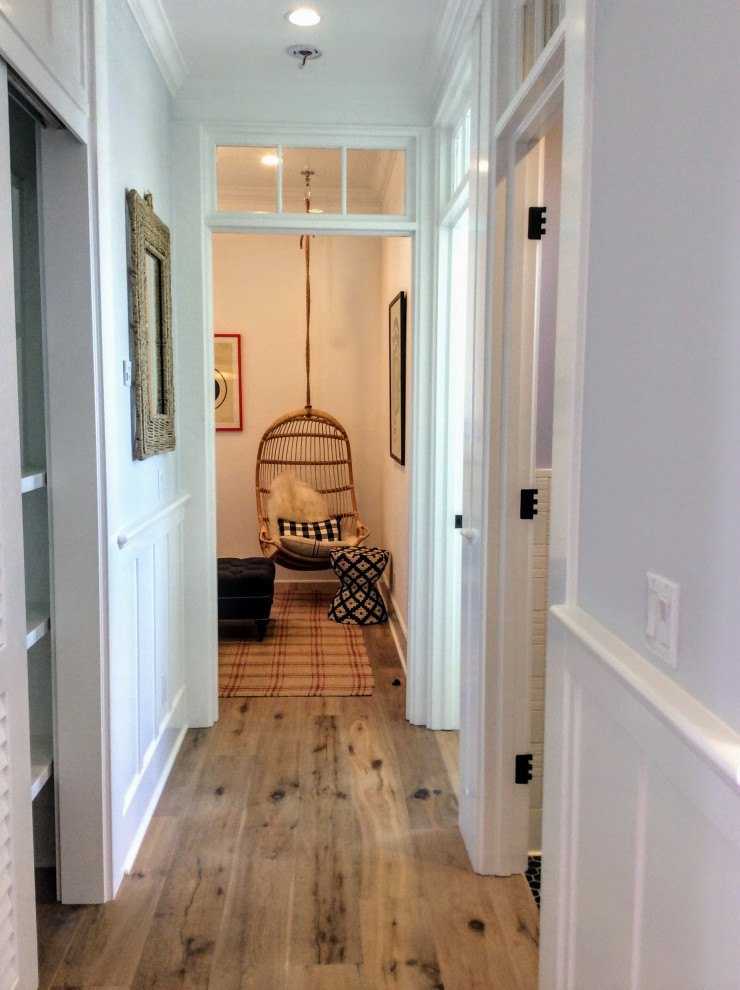 This is an example of a mid-sized beach style hallway in Miami with grey walls, light hardwood floors, brown floor, recessed and decorative wall panelling.