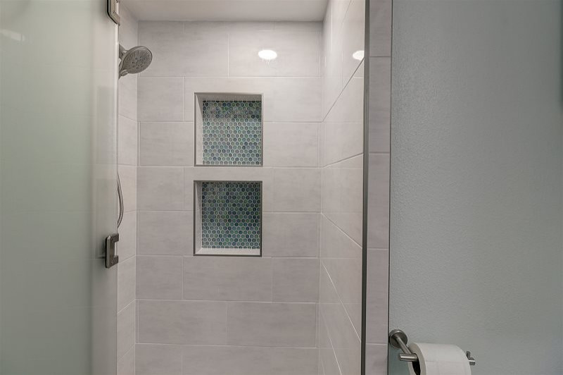 Design ideas for a mid-sized beach style bathroom in Austin with shaker cabinets, white cabinets, an open shower, a one-piece toilet, white tile, ceramic tile, blue walls, porcelain floors, an undermount sink, quartzite benchtops, grey floor, a shower curtain, beige benchtops and a single vanity.