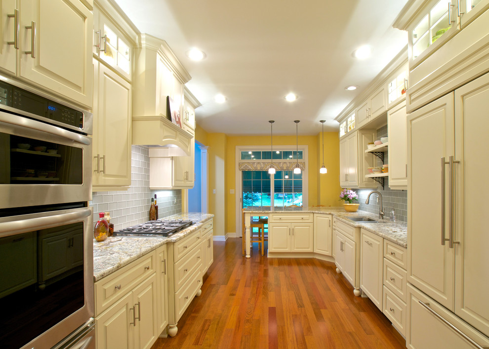 Traditional galley eat-in kitchen in New York with an undermount sink, raised-panel cabinets, white cabinets, granite benchtops, grey splashback, stainless steel appliances and medium hardwood floors.