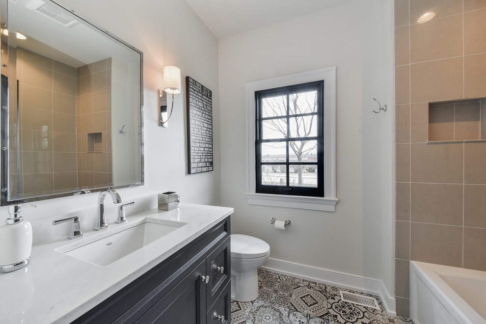 This is an example of a mid-sized transitional 3/4 bathroom in Chicago with recessed-panel cabinets, grey cabinets, an alcove tub, a shower/bathtub combo, beige tile, grey walls, cement tiles, an undermount sink, quartzite benchtops, multi-coloured floor and white benchtops.