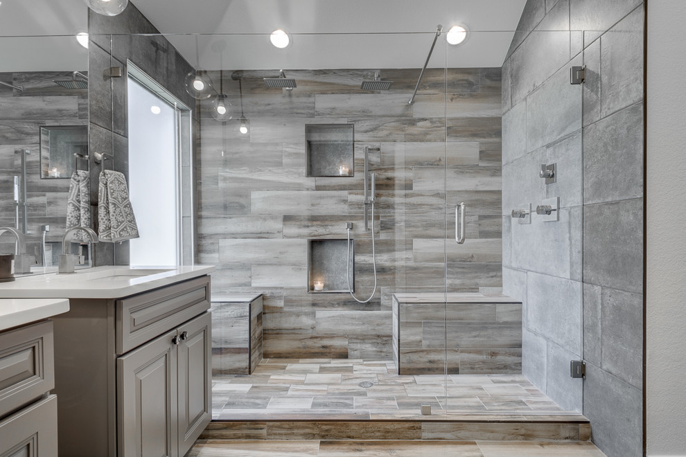 This is an example of a large modern master bathroom in Dallas with grey cabinets, gray tile, a drop-in sink, quartzite benchtops, raised-panel cabinets, an alcove shower, a two-piece toilet, cement tile, white walls, porcelain floors, multi-coloured floor, a hinged shower door and white benchtops.