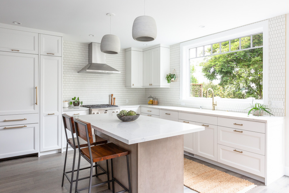 Foto på ett mellanstort lantligt vit kök, med en undermonterad diskho, skåp i shakerstil, vita skåp, bänkskiva i kvartsit, vitt stänkskydd, stänkskydd i keramik, integrerade vitvaror, mellanmörkt trägolv, en köksö och grått golv