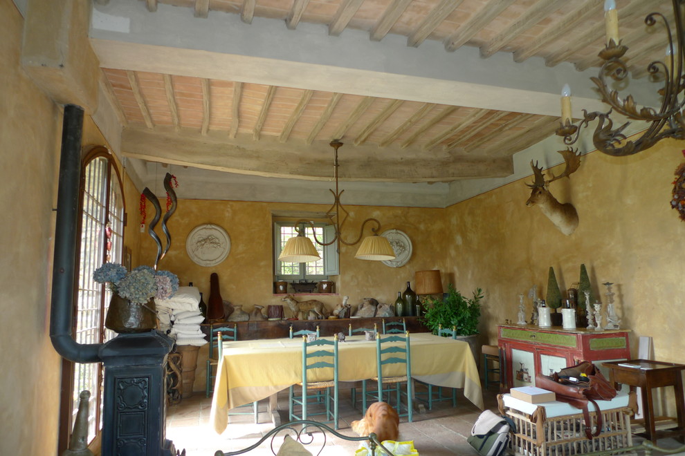Idee per una sala da pranzo country con pareti gialle, stufa a legna e cornice del camino in metallo