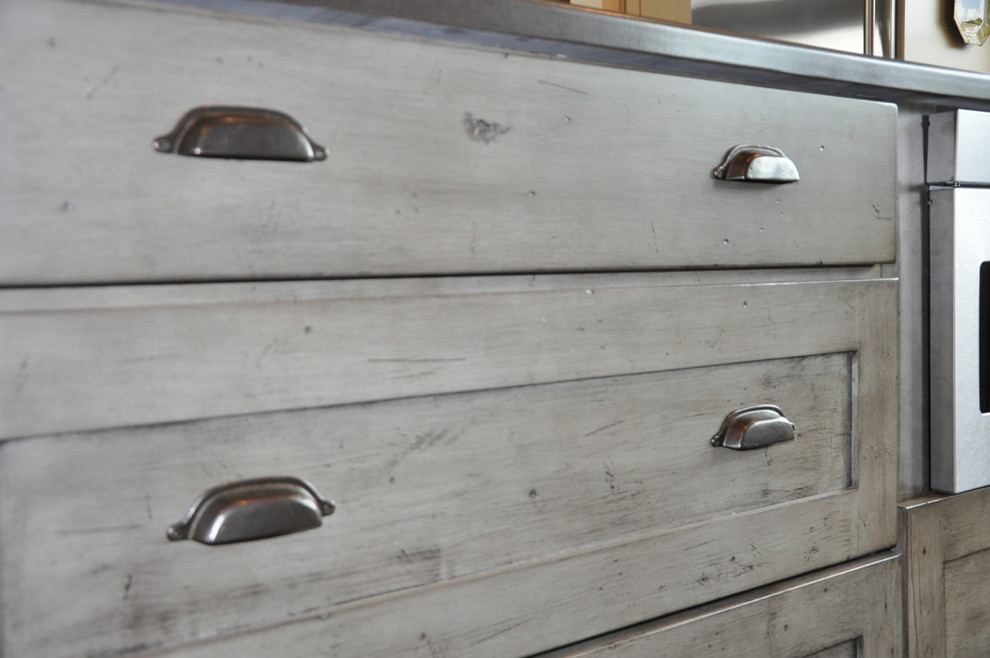 Inspiration for a large rustic l-shaped medium tone wood floor eat-in kitchen remodel in Seattle with an undermount sink, shaker cabinets, distressed cabinets, quartz countertops, gray backsplash, stone tile backsplash, stainless steel appliances and an island