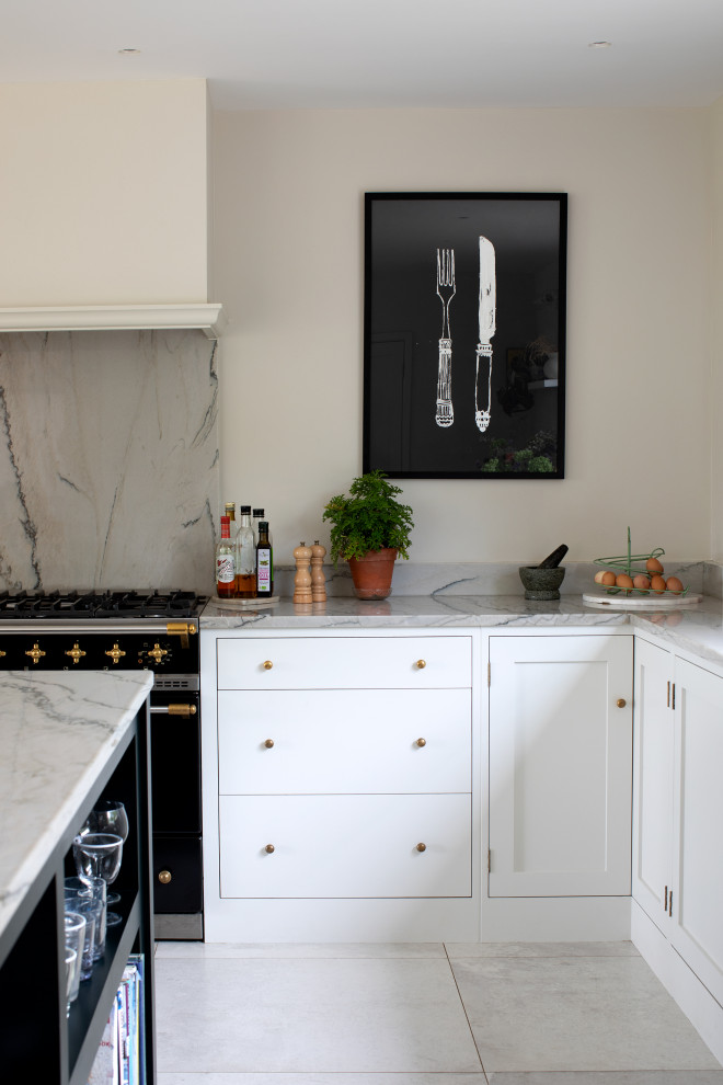 This is an example of a large contemporary cream and black l-shaped open plan kitchen in Oxfordshire with a built-in sink, flat-panel cabinets, black cabinets, marble worktops, grey splashback, marble splashback, black appliances, marble flooring, an island, white floors and grey worktops.