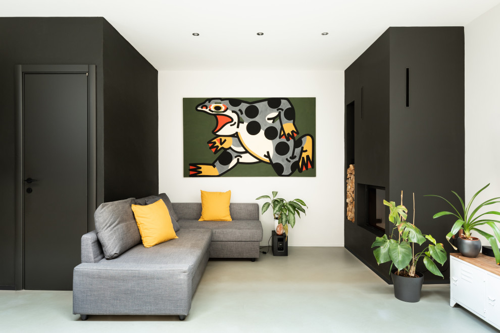 Imagen de salón abierto nórdico de tamaño medio con paredes grises, suelo de cemento, chimenea de esquina, marco de chimenea de yeso y suelo gris