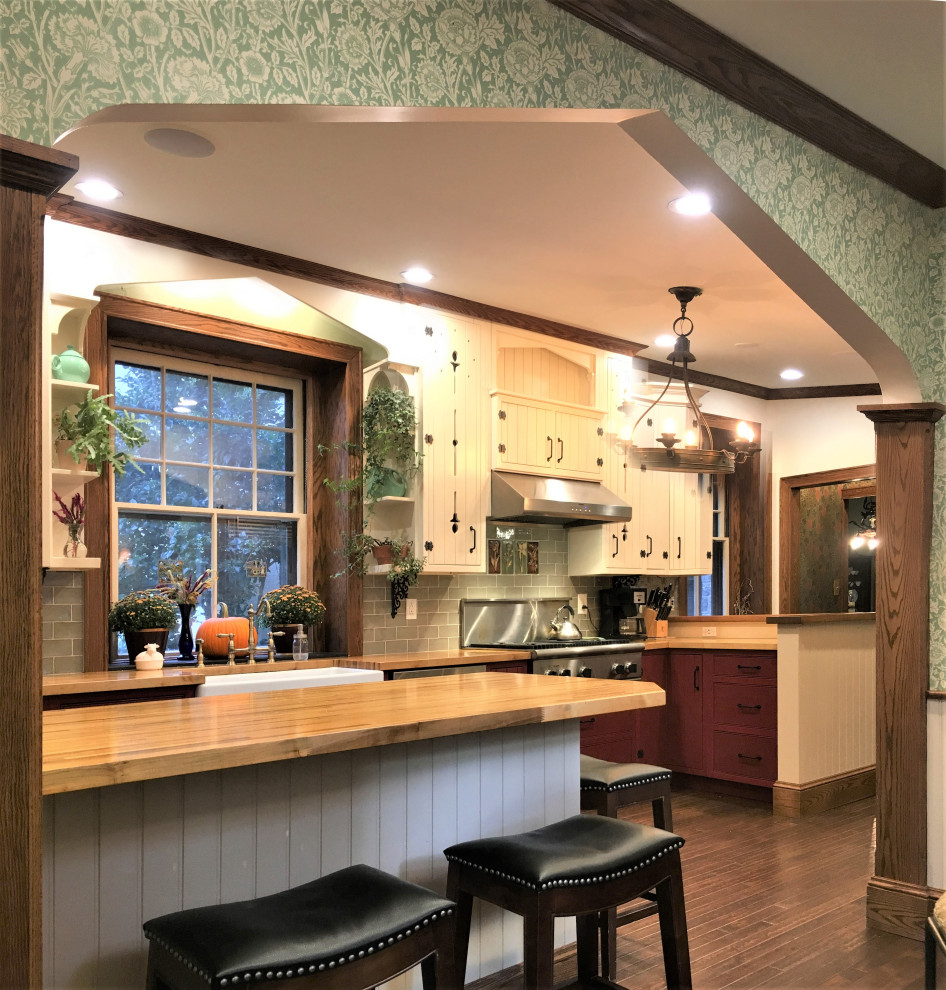 This is an example of a large traditional l-shaped open plan kitchen in Philadelphia with a farmhouse sink, beaded inset cabinets, white cabinets, wood benchtops, green splashback, porcelain splashback, stainless steel appliances, medium hardwood floors, multiple islands, brown floor and brown benchtop.