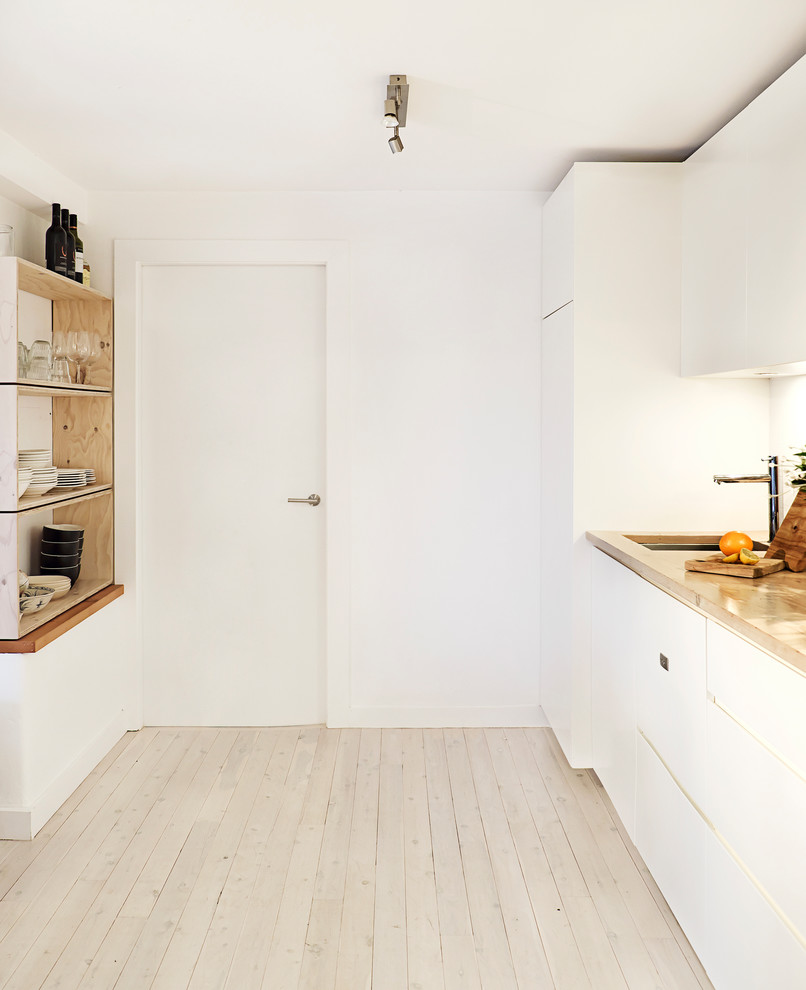 Scandinavian single-wall kitchen in Sydney with an undermount sink, flat-panel cabinets, white cabinets, light hardwood floors and no island.
