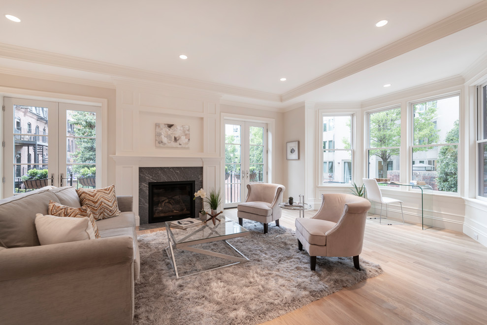 This is an example of a transitional open concept living room in Boston with white walls, light hardwood floors, a standard fireplace, a stone fireplace surround and recessed.