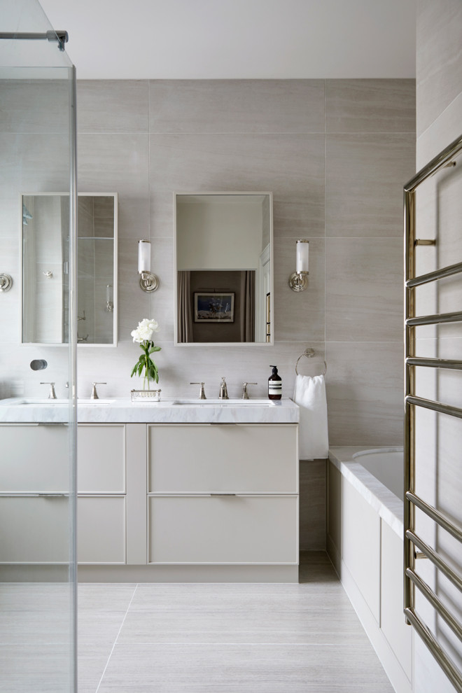 Transitional master bathroom in London with recessed-panel cabinets, beige cabinets, a drop-in tub, a corner shower, beige tile, porcelain tile, beige walls, porcelain floors, a drop-in sink, marble benchtops, beige floor, a hinged shower door, white benchtops, an enclosed toilet, a double vanity and a built-in vanity.