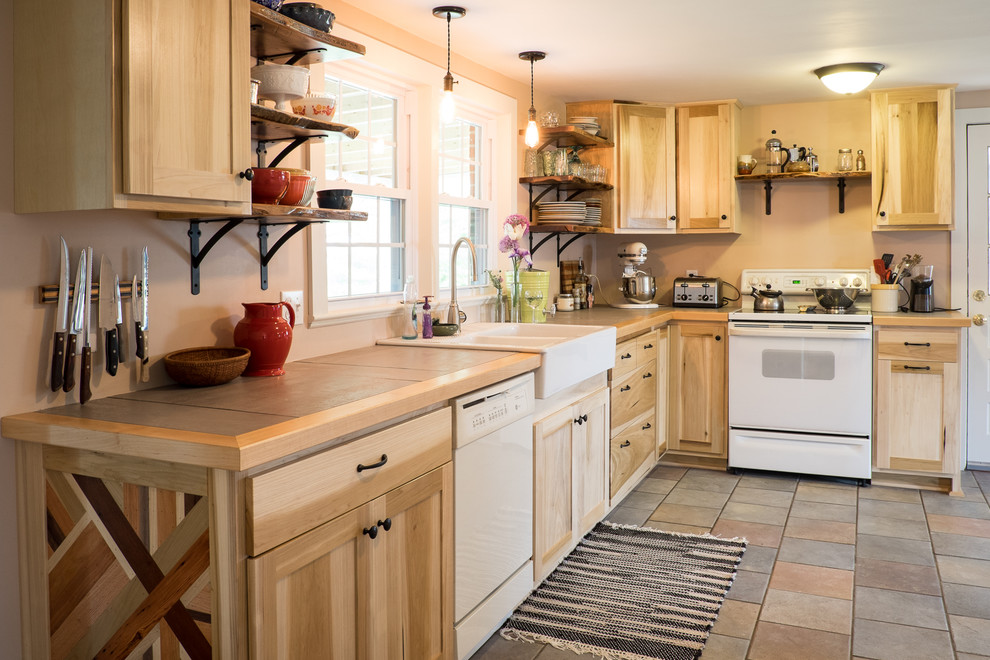 Design ideas for a mid-sized country l-shaped eat-in kitchen in DC Metro with a farmhouse sink, flat-panel cabinets, light wood cabinets, tile benchtops, white appliances, ceramic floors and no island.