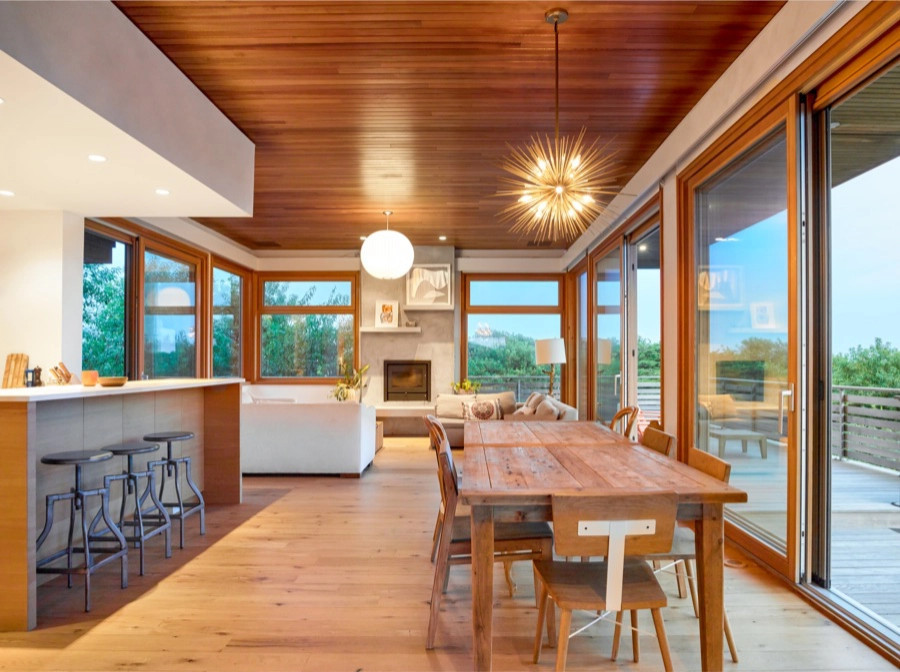 Идея дизайна: кухня-столовая в морском стиле с паркетным полом среднего тона, стандартным камином и деревянным потолком