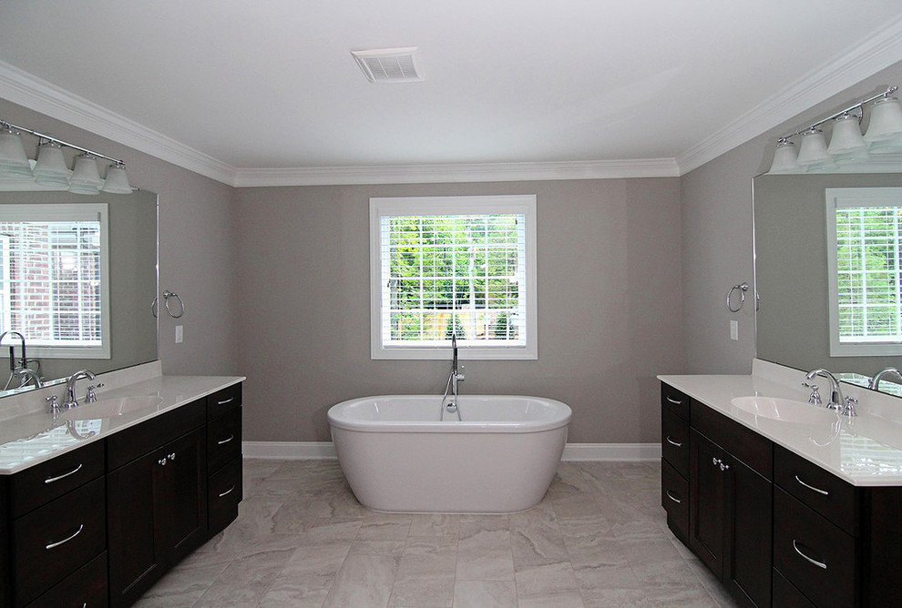 Photo of a large traditional master bathroom in Raleigh with recessed-panel cabinets, dark wood cabinets, a freestanding tub, a corner shower, a one-piece toilet, grey walls, ceramic floors, white floor, a hinged shower door and white benchtops.
