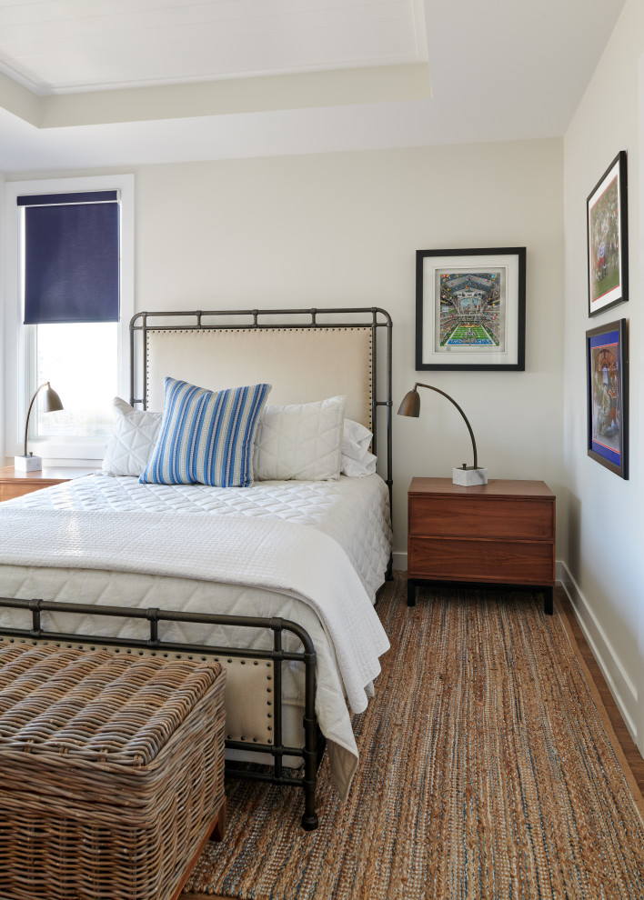This is an example of a beach style bedroom in New York with beige walls and brown floor.