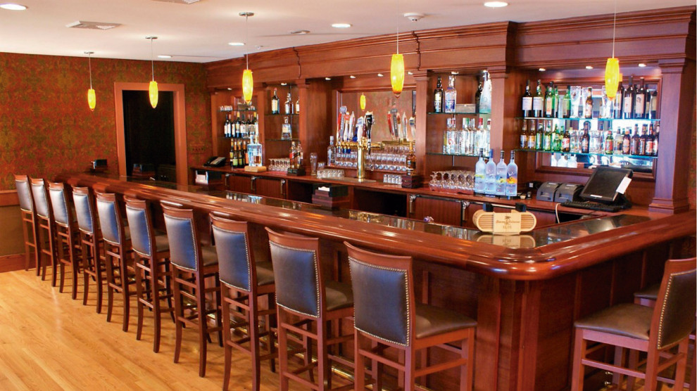 Photo of a large traditional single-wall home bar in New York with brown cabinets, wood benchtops, brown splashback, timber splashback and brown benchtop.