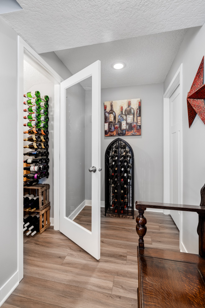 Large vinyl floor and brown floor wine cellar photo in Other with storage racks