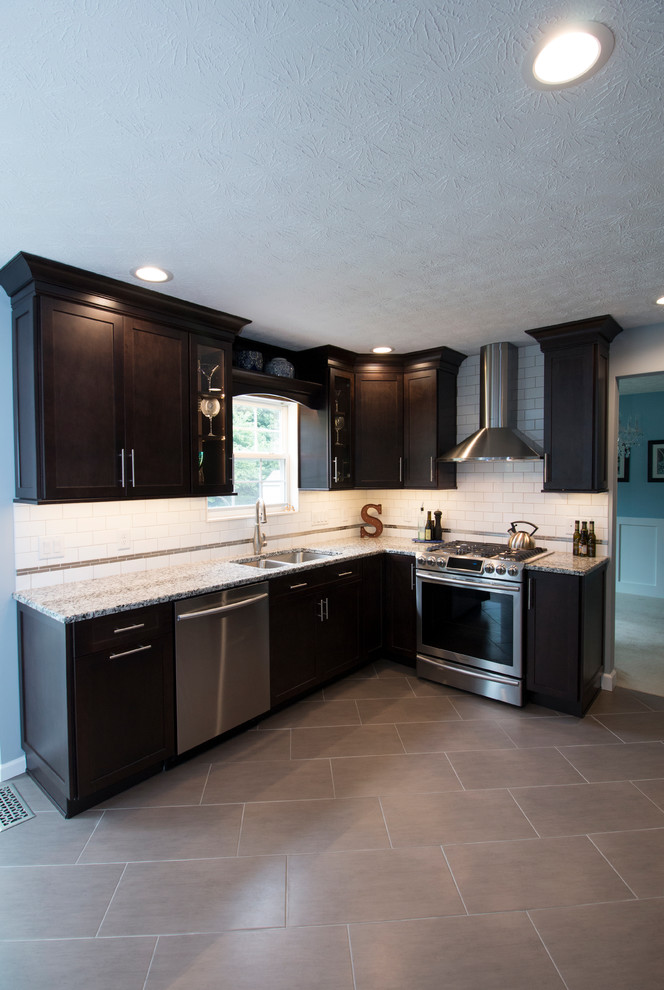 Mid-sized trendy ceramic tile kitchen photo with an undermount sink, shaker cabinets, dark wood cabinets, granite countertops, white backsplash, subway tile backsplash, stainless steel appliances and a peninsula