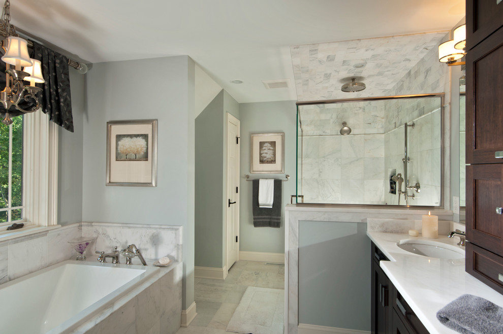 Photo of a mid-sized traditional master bathroom in Boston with recessed-panel cabinets, dark wood cabinets, a drop-in tub, a corner shower, white tile, marble, grey walls, marble floors, an undermount sink, quartzite benchtops, white floor, a hinged shower door and white benchtops.