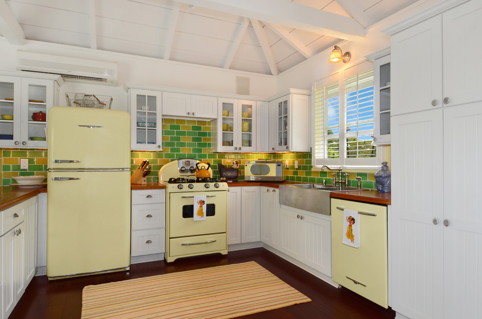 Design ideas for a tropical u-shaped kitchen in Hawaii with green splashback, coloured appliances, a farmhouse sink, beaded inset cabinets, white cabinets, subway tile splashback, dark hardwood floors and no island.